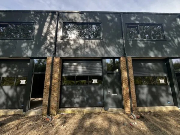 Voorgevel van nieuwbouw bedrijfsunits 9, 10 en 11 aan de Broekdijk West met donkere gevelbekleding en bakstenen pilaren.